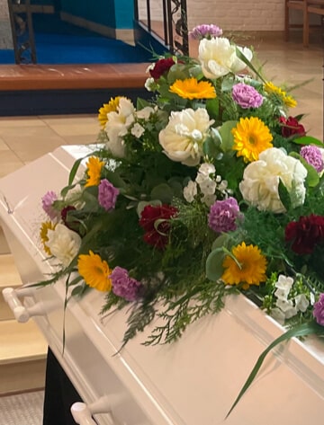 Blomster på hvid kiste i kirke